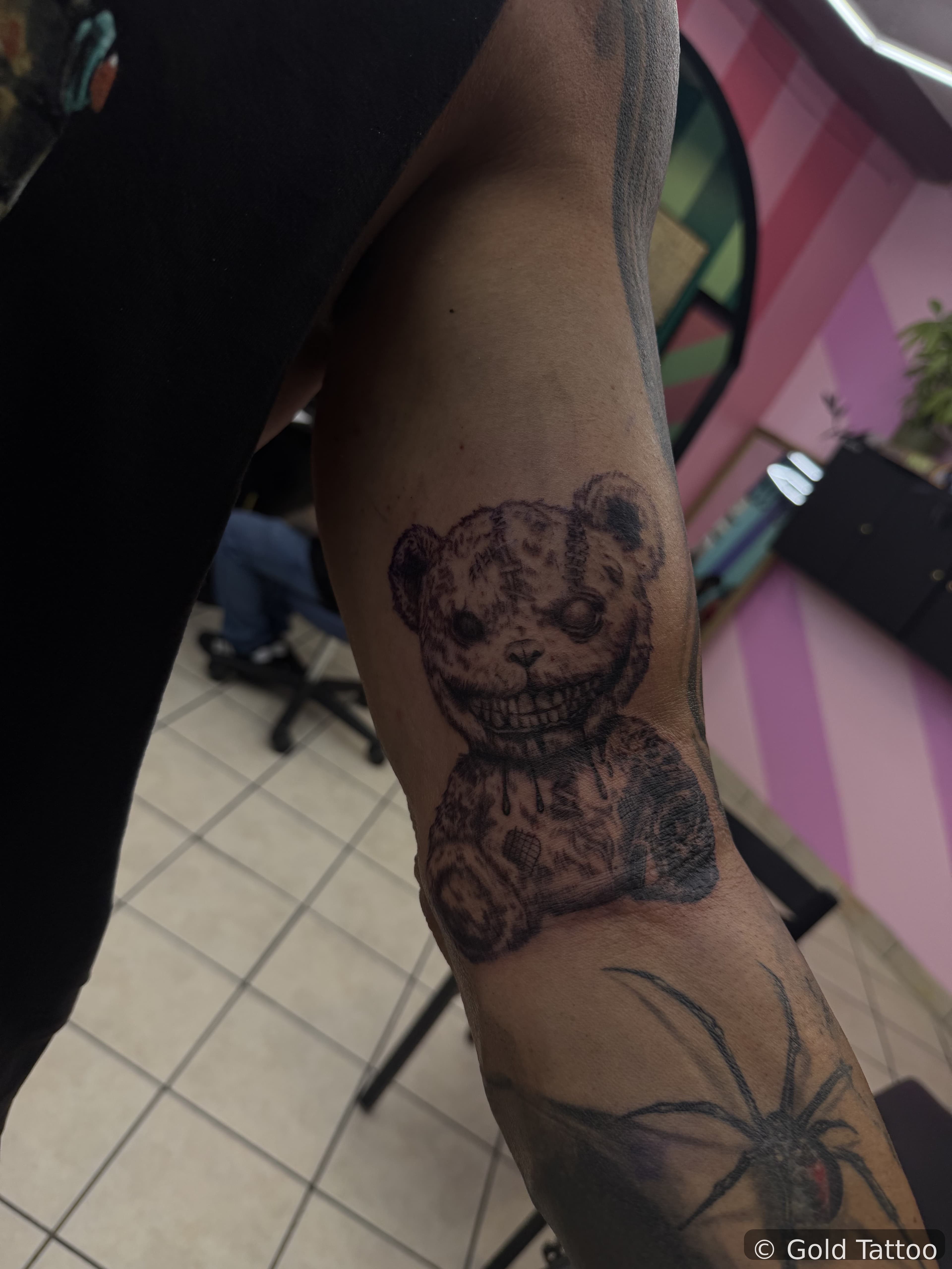 Black and grey creepy teddy bear tattoo on an arm by Gia “DOC” at Gold Tattoo, 1506 S Las Vegas Blvd, Unit 3