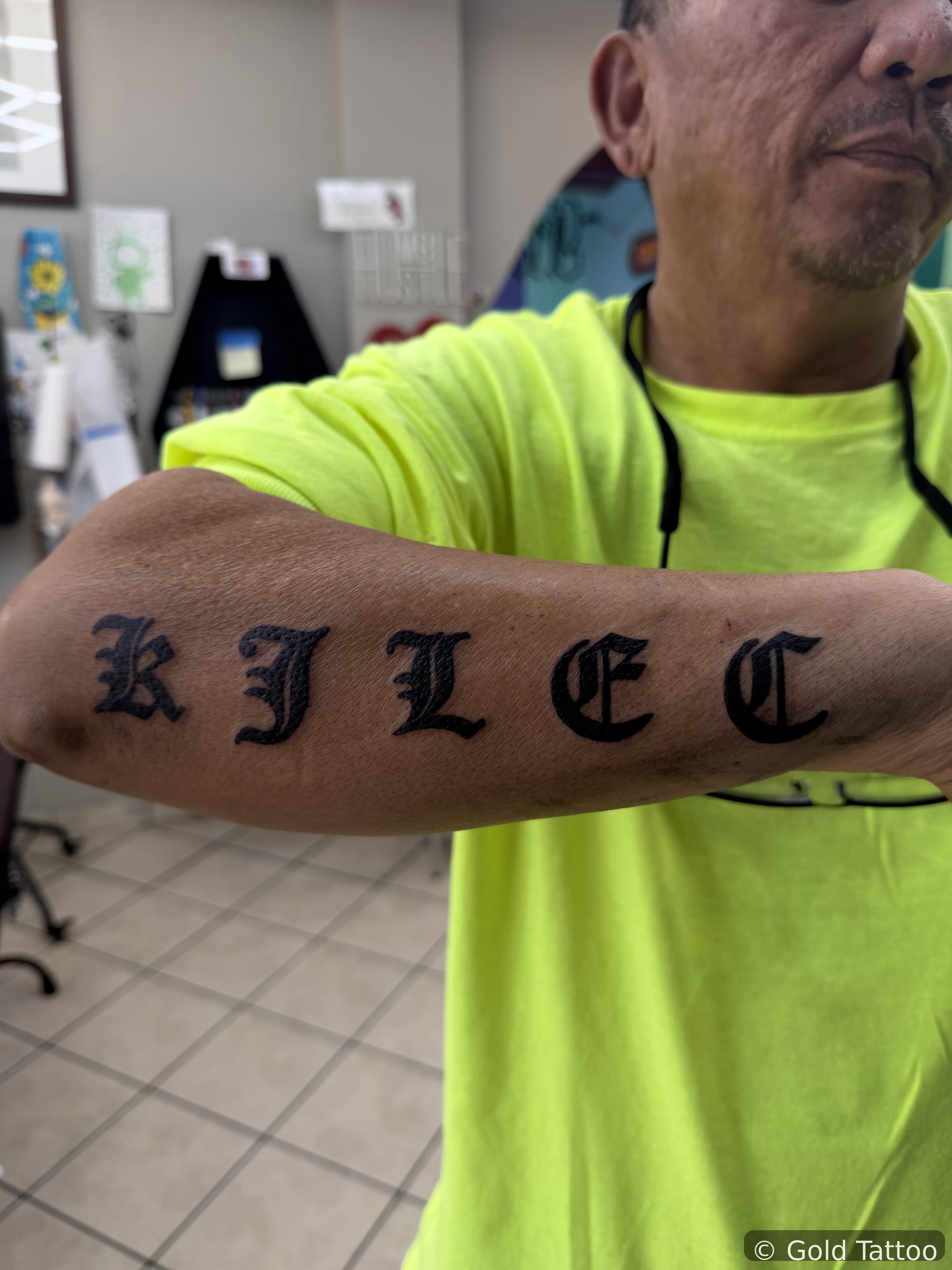 Old English lettering tattoo across a forearm by Gia “DOC” at Gold Tattoo, 1506 S Las Vegas Blvd, Unit 3