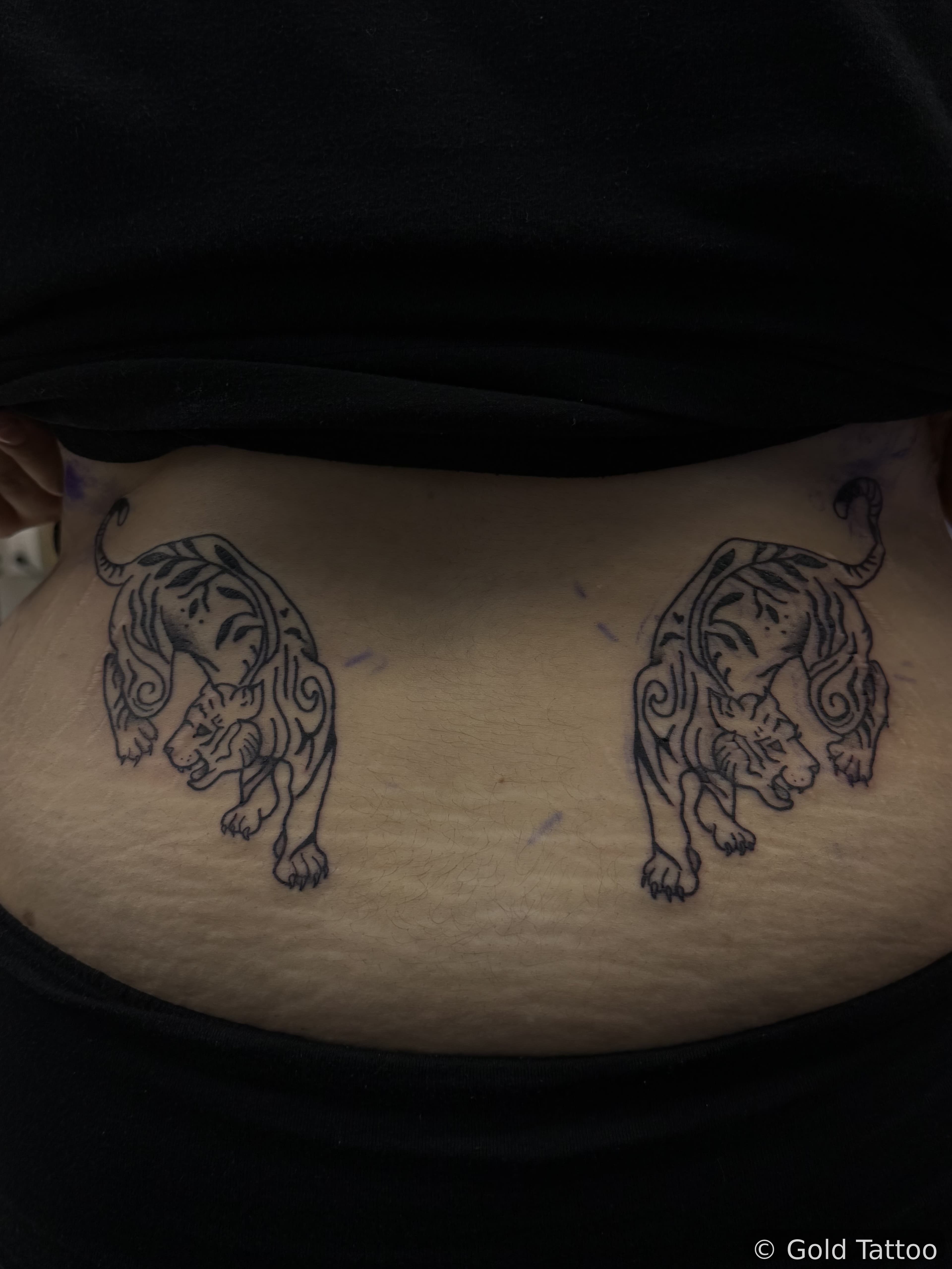Pair of black linework tiger tattoos on a lower back by Gia “DOC” at Gold Tattoo, 1506 S Las Vegas Blvd, Unit 3