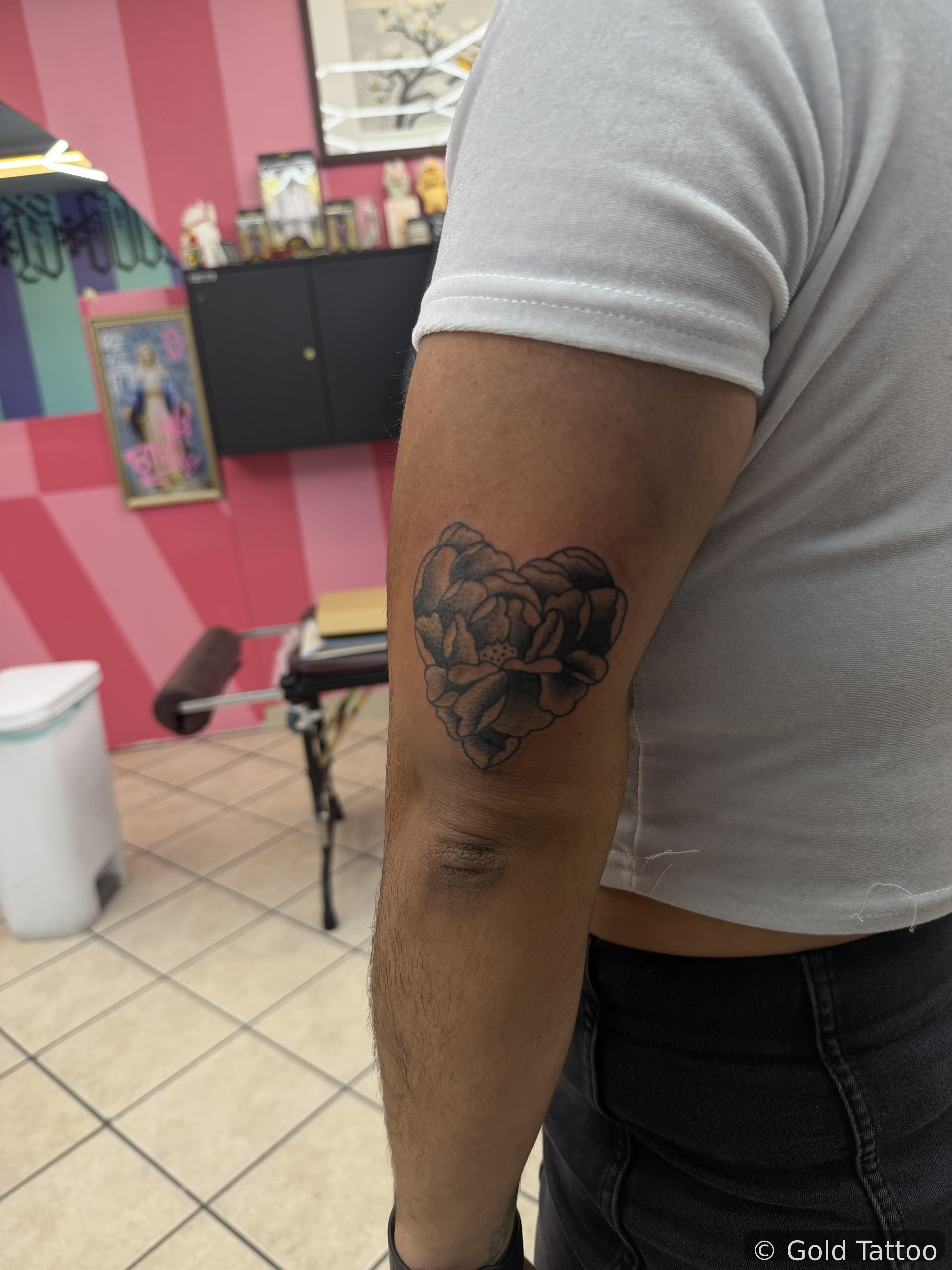 Black and grey heart-shaped peony tattoo above the elbow by Gia “DOC” at Gold Tattoo, 1506 S Las Vegas Blvd, Unit 3, a short walk from the STRAT